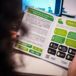 Grass Ceiling has been recognised as a Horizon Europe success story. In this image there is a woman holding a leaflet with the project outputs